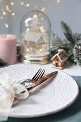 Christmas place setting with plate, cutlery and festive decor on table, closeup