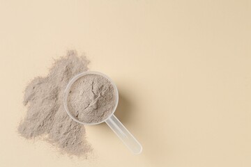 Protein powder and scoop on beige background, top view. Space for text