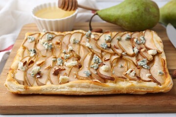 Delicious puff pastry tart with pears, almond and blue cheese on light table, closeup