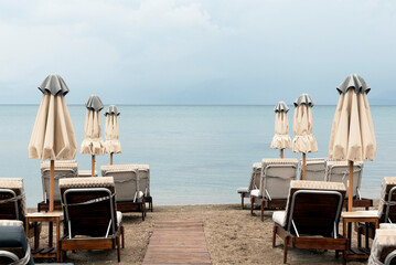 View of beach on cloudy day with sunbeds and closed parasols
