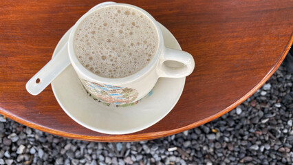 a cup of coffee sits on a table next to a plate of cups.