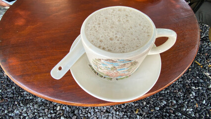 a cup of coffee sits on a table next to a plate of cups.