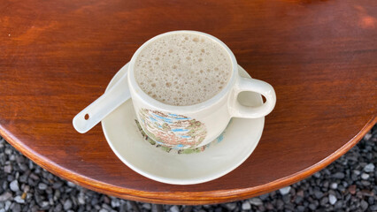 a cup of coffee sits on a table next to a plate of cups.