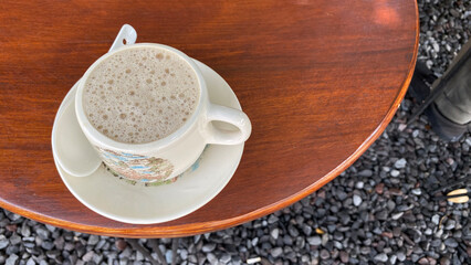 a cup of coffee sits on a table next to a plate of cups.