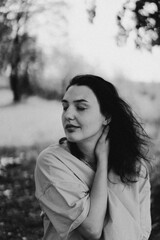 A woman in a bright yellow top walks through a park, smiling happily as she enjoys the beauty of nature and the warmth of the sun in autumn.