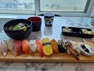 Cold soba noodles and sushi with rice and a variety of fish, served on a wooden plate