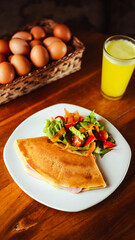Crepas saladas con jamón, queso con una deliciosa ensalada, una cesta con huevos y un jugo natural refrescante