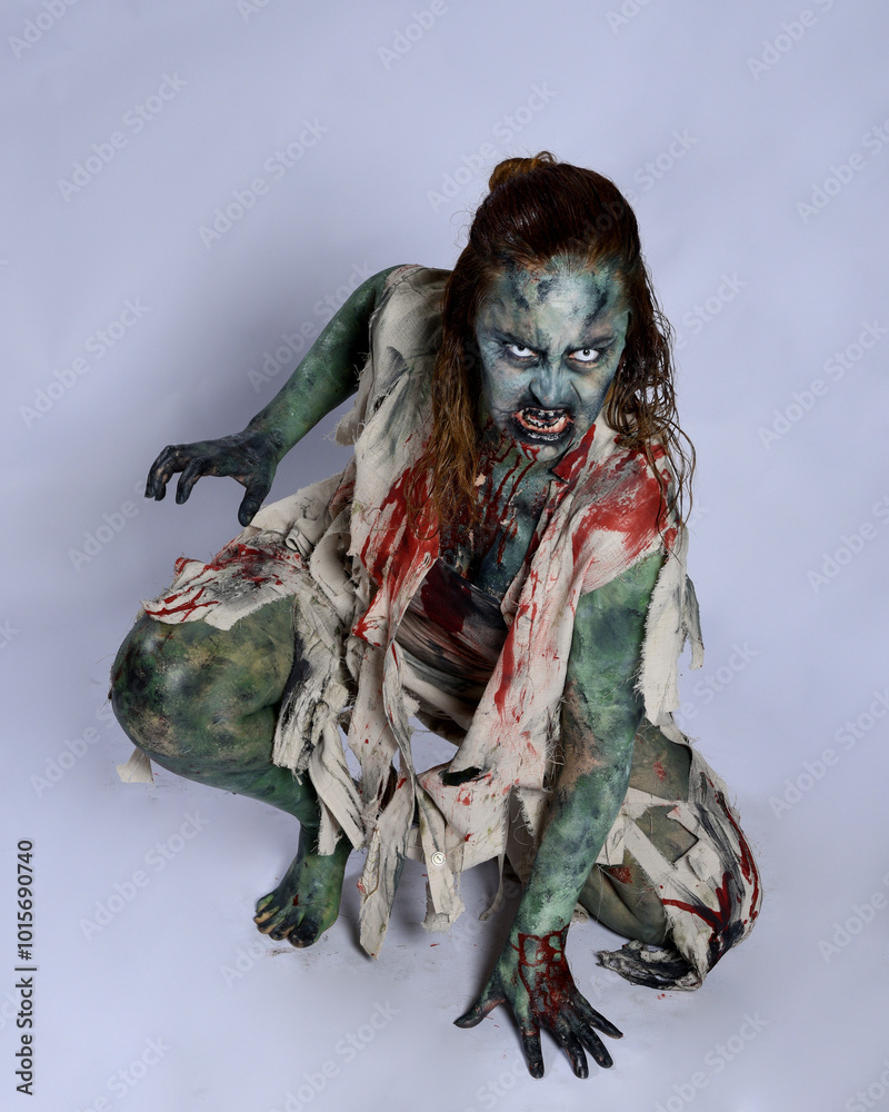 Canvas Prints portrait of scary female model wearing spooky halloween costume, ripped clothes and fake blood like an undead demon apocalyptic zombie character. Isolated figure, crawling poses dark studio background