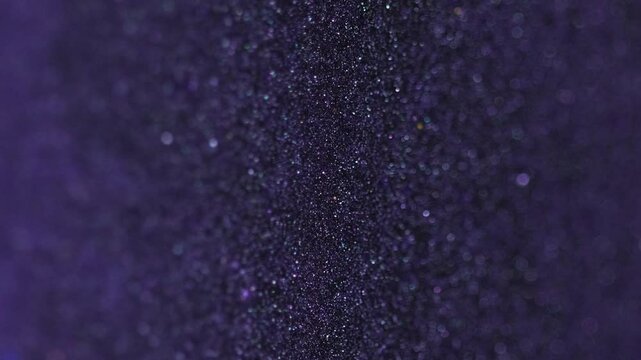 Sparkling ink spill. Glitter paint flow. Blur purple black color shiny metallic sequin sand particles fluid wave motion abstract art background with bokeh lights.