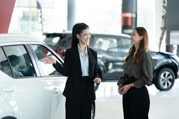 Saleswoman Showing Car To Female Customer At Showroom