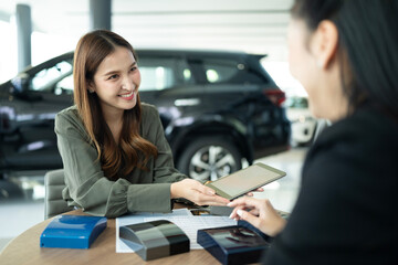 Car Dealer Using Digital Tablet Showing Color Sample To Female Customer At Showroom