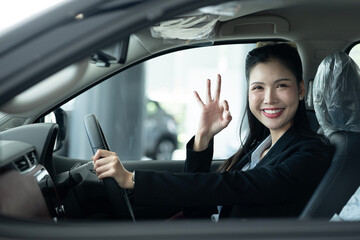 Woman Gesturing OK Sign Inside The Car At Showroom