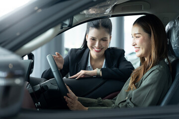 Saleswoman Showing Interior Of A Car To Businesswoman At Showroom