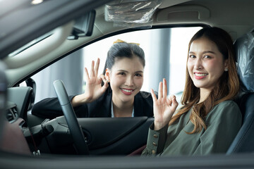 Saleswoman and  female customer gesturing OK sign inside the car at showroom..4K Saleswoman Showing Car To Female Customer At Showroom