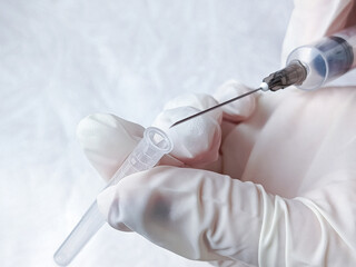 Hands in medical gloves remove cap from syringe needle. Opening syringe. Routine vaccinations for...