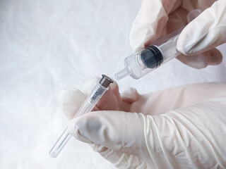 Hand in medical glove removes needle from syringe. Puts needle on syringe for injection. Antibiotic injection. Vaccination. Sterility in medicine, hospital.
