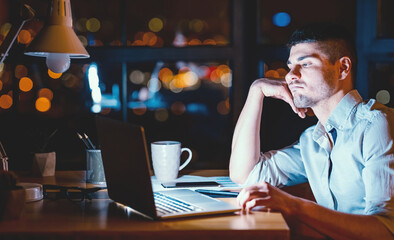 Boring Job. Overworked Business Guy Sitting At Laptop Uninterested In Work In Modern Office At Night. Low Light