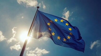 European Union Flag Waving Against a Bright Blue Sky with Sunlight and Clouds in the Background