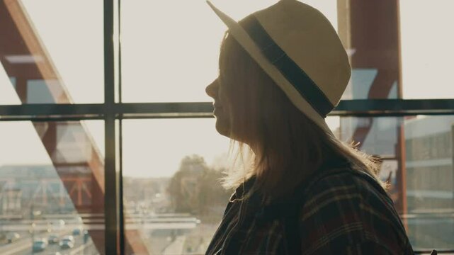Female tourist walking in the airport with a suitcase in the sun rays.