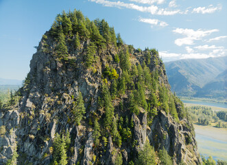 A mountain covered in trees with a river in the background