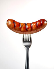 Grilled sausages on a fork on a white background