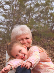 Fototapeta premium Loving cute granddaughter hugging her grandmother. Happy family. Having good times with grandparent outdoors. Love, connection, bonding concept
