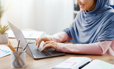 Smiling Arabic Woman Working On Laptop For New Project At Workplace In Office, Cropped Image With...