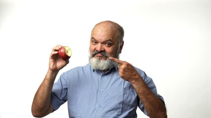 An Indian Asian elderly businessman with a beard is enjoying an apple, highlighting its health benefits gesturing with hands