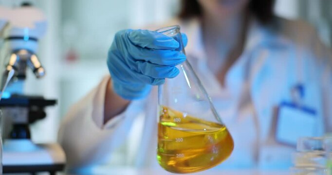 Scientist holding flask with yellow liquid in laboratory