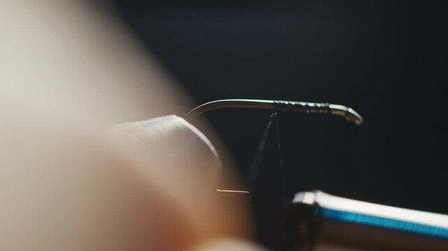 Person wraps thread around the hook during tying the fishing fly. Macro studio footage of the fishing fly tying process