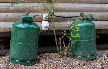 Two green gas tanks are sitting on the ground next to a wooden wall