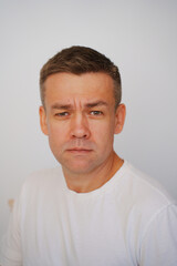 Obraz premium Portrait of a middle-aged man in a white t-shirt on a white background. photo posing. men's physical and mental health. half a turn