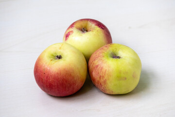 Fresh ripe apples on a light wooden surface.