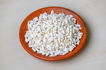 Popped rice or Khoi, served on a clay plate on a wooden background. It is traditional and popular Bengali snack.