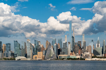 Fototapeta premium Manhattan skyline under a bright blue sky with fluffy clouds.
