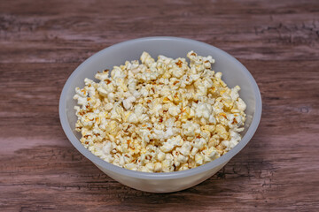 A bowl of popcorn is sitting on a wooden table