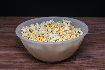 A bowl of popcorn is sitting on a wooden table