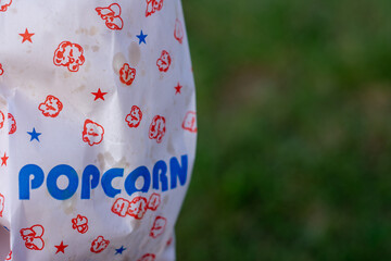 A bag of popcorn is sitting on a green grassy field