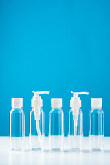 Clear plastic bottles with pumps arranged on a table against a bright blue background