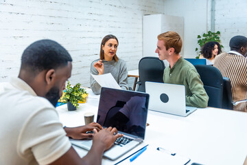 Multiracial people working using laptop in a coworking