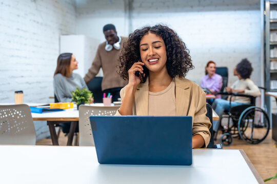 Cheerful woman talking to the mobile while working at coworking