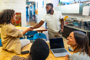 African man shaking hands with colleagues arriving at a coworking