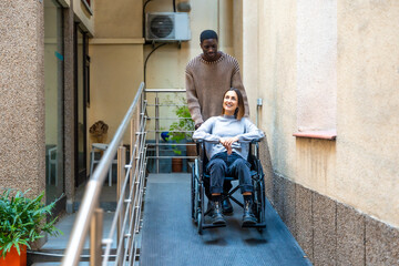 African man pushing the wheelchair of disabled colleague at coworking