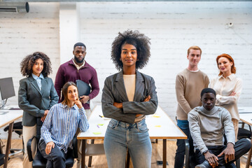Fototapeta premium Confident african woman standing with arms crossed next to colleagues