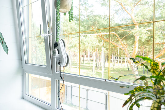 A window cleaner robot cleans windows in a house from the inside. Cleaning assistant, safe window cleaning, remote control
