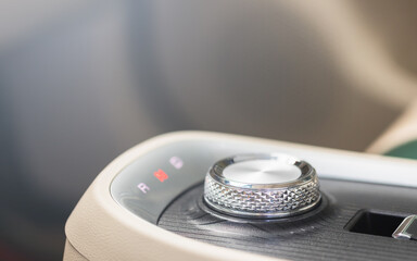 A hand rotating the gear selector in an electric vehicle, EV transmission system works. Seamless and innovative gear-shifting technology, emphasizing the simplicity and efficiency of modern EV systems