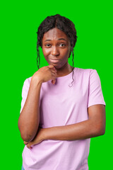 Thoughtful woman pondering in front of a bright green background during a casual moment