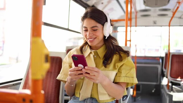 Beautiful, young Latin woman riding in the city bus and using smartphone