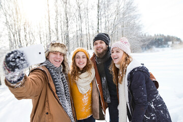 Portrait of friends taking selfie the snowy nature. First snowfall of the season.