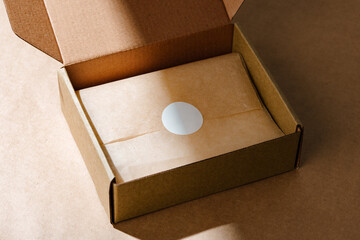 A sealed kraft box containing a wrapped item, positioned on a textured brown surface for an unboxing experience